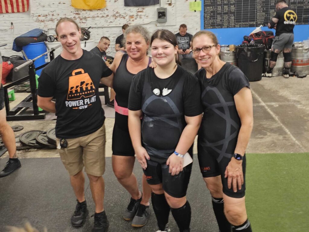 women with coach at powerlifting meet