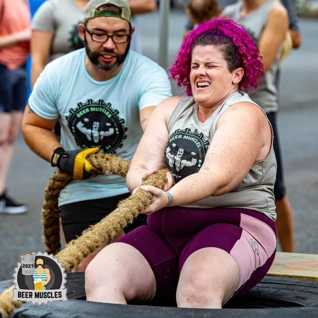 Jess at Beer Muscles 2021 doing an arm over arm truck pull